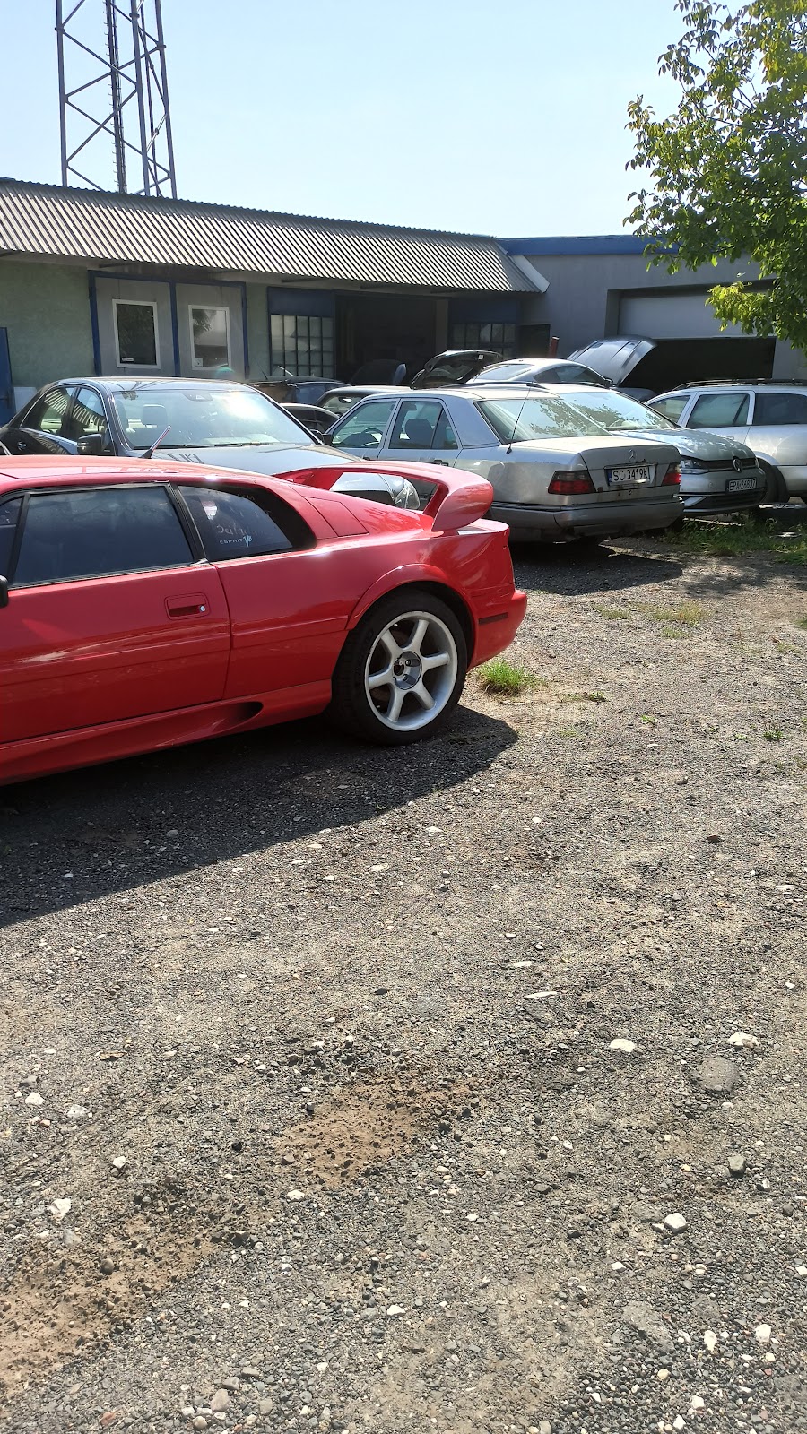 Czerwony klasyczny Lotus i Mercedes na placu warsztatu Adicar